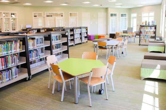 Row of pentagonal tables with chairs arranged by low shelving